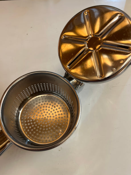 Stainless-steel ricer and masher for potatoes, fruit, and juice, featuring a solid one-piece design with a hinged lid and perforations for efficient mashing and straining.