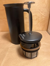 Espro French press with black carafe and separate plunger assembly, featuring a metal mesh filter for precise coffee brewing. Ideal for a rich, smooth cup.