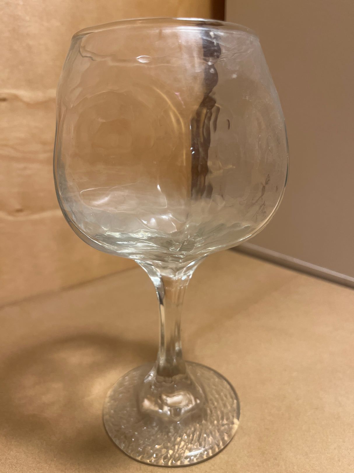 Libbey Chivalry glassware featuring a clear, dimpled goblet-style glass with a rounded bowl, slender stem, and textured circular base on a tan surface.