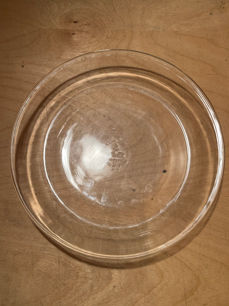 Vintage glass Fire-King Anchor Hocking 460 pie plate on wooden surface, showcasing its clear, round design ideal for even baking.