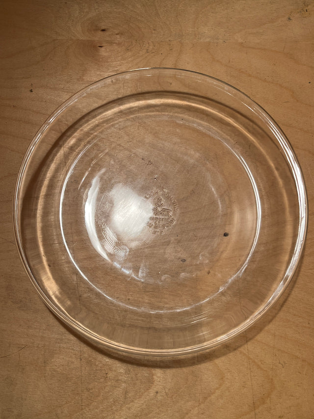 Vintage glass Fire-King Anchor Hocking 460 pie plate on wooden surface, showcasing its clear, round design ideal for even baking.