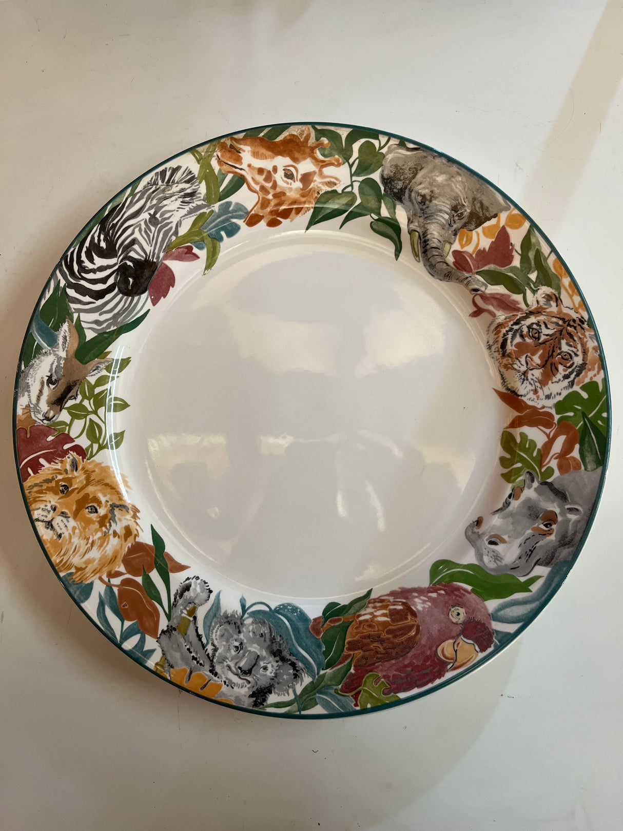 Jungle Fever dinner plate by Deborah Mallow for Sango 3033, featuring animal heads like giraffe, elephant, and zebra around its rim.