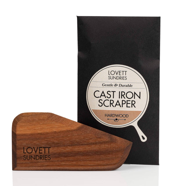 Hard Wood Cast Iron Pan Scraper set, featuring a wedge-shaped hardwood scraper engraved with “Lovett Sundries,” packaged in a black sleeve labeled “Gentle & Durable.”