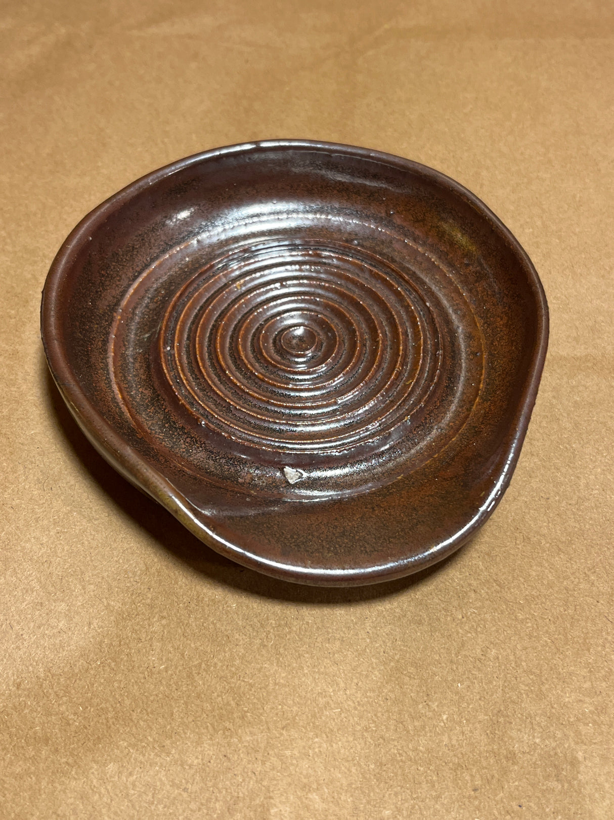 Handmade ceramic garlic grater spoon rest by Charles Lehman, featuring a rich, mottled brown glaze with concentric raised rings, perfect for kitchen display.