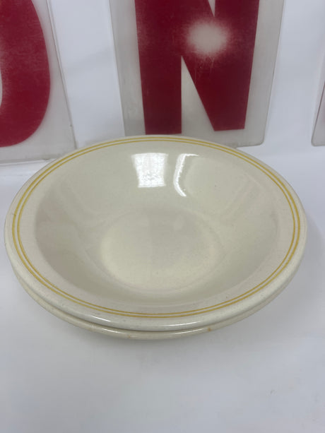 Ceramic butter yellow pasta bowls set of 2, featuring a butter yellow base with darker rings around the rim. One bowl has a small underside chip.