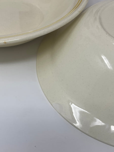 Ceramic butter yellow pasta bowls set of 2, showcasing a close-up of the bowl's smooth surface and rim. One bowl has a minor underside chip.