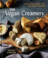 Cover of The Vegan Creamery cookbook featuring assorted homemade vegan cheeses on a wooden board with figs, pears, crackers, and a cheese knife.