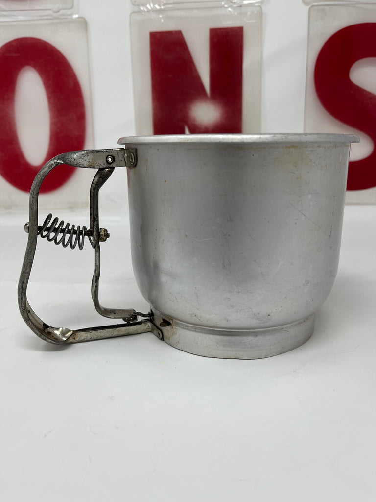 Foley aluminum 5-cup flour sifter with metal cup and spring mechanism, shown close-up, highlighting its vintage design and functional handle.