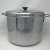 A Century Ware stock pot with a steamer basket, featuring a large silver pot with a black lid and metal handle. Kitchenware for versatile cooking.