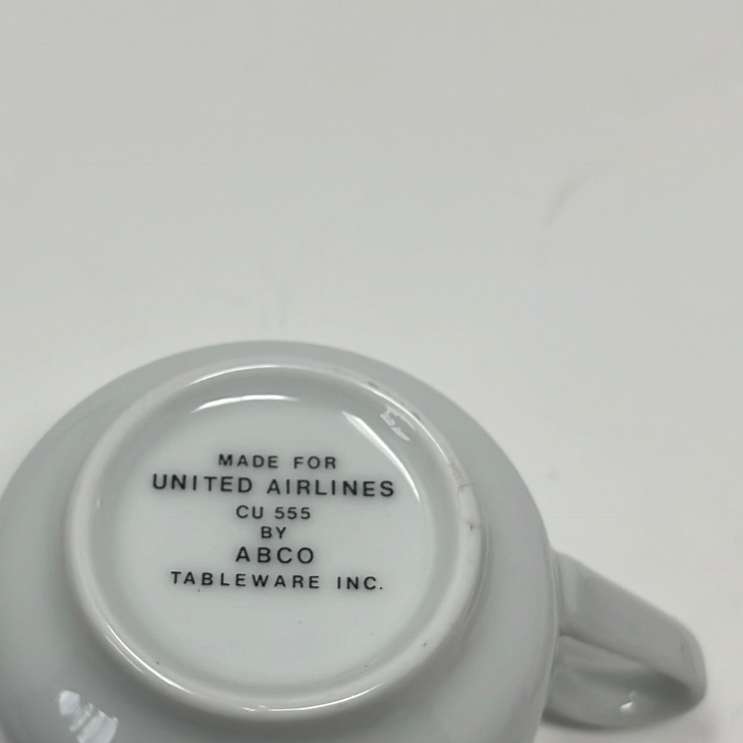 ABCO espresso cup with gold trim for United Airlines, showcasing slight wear on rim. Close-up of white cup with black text, label, and number.