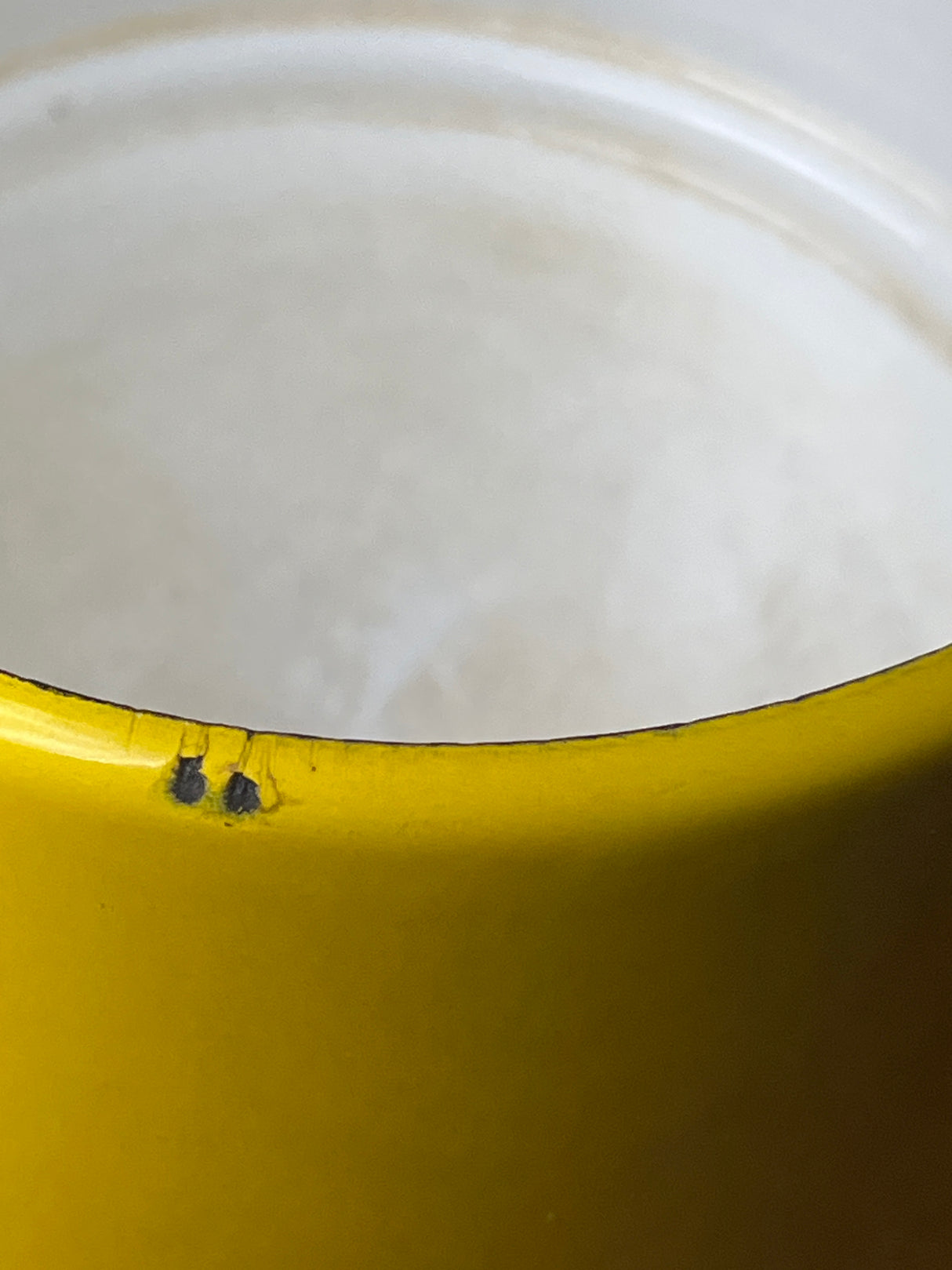 Close-up of the vintage Michael Lax Copco fondue pot, showcasing a chipped yellow enamel rim with exposed metal underneath, highlighting its retro charm.