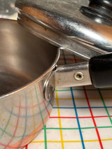 3/4-qt saucepan with copper bottom - vintage Revere Ware stainless steel, stacked with lid on black-handled saucier, showcasing durable construction and efficient heat distribution.