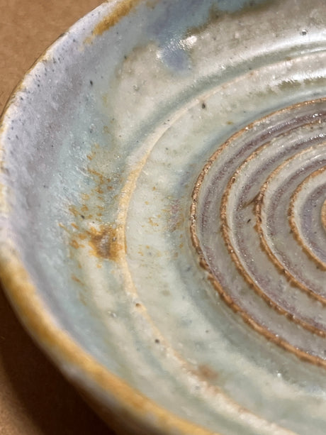 Handmade ceramic garlic grater spoon rest by Charles Lehman, featuring concentric throwing lines and a subtle glaze, combining beauty and functionality for kitchen display.