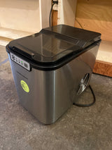Portable countertop ice maker - Hamilton Beach, featuring a stainless-steel finish, top lid, front control panel, and side ventilation fan, ideal for producing 26 lbs. of ice daily.