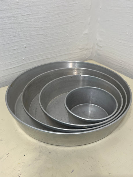 Set of 4 Aluminum Vitality by Mirro four-tier wedding cake pans, showcasing nested vintage 1950s aluminum pans for superior heat distribution and rust-resistant durability.