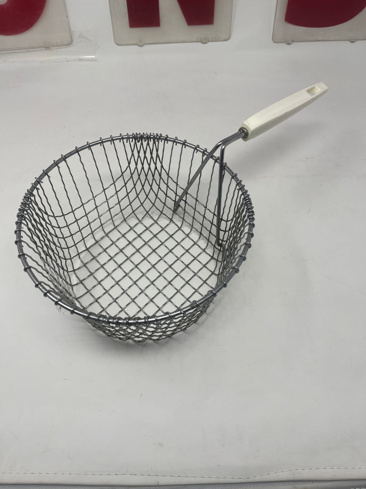 Alloyed steel deep-fryer basket with a removable white resin handle, designed for efficient frying and easy cleaning, featuring a sturdy wire construction.