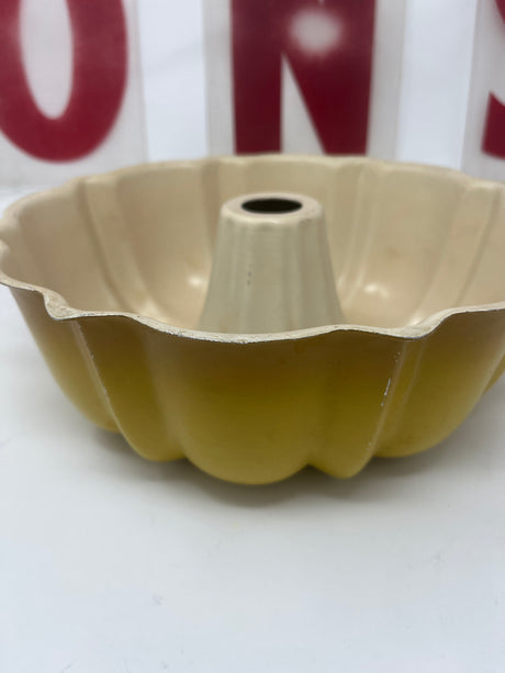 Yellow ombré aluminum bundt cake pan with vintage 1970s design, featuring an enamel coating with minor scratches, perfect for adding a retro touch to baking.
