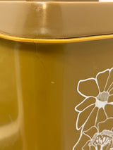 Close-up of a mustard Melmac container with a white floral decal and a crack near the lid, part of a retro storage set of four.