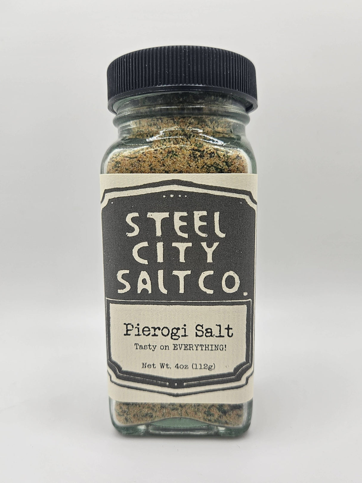 NEW Pierogi Salt! Square glass jar with black lid, filled with herb-flecked seasoning, labeled Steel City Salt Co. Pierogi Salt – Tasty on EVERYTHING!