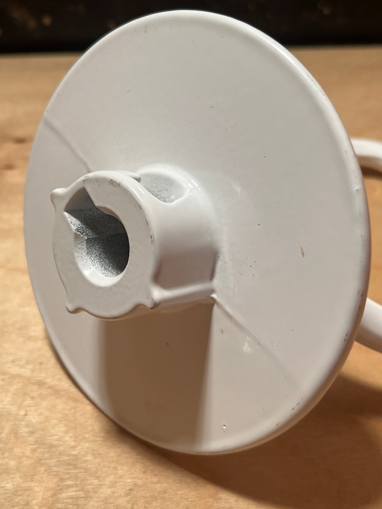 Dough hook attachment for Kitchenaid stand mixer, resembling a spring-roller window shade end-cap with a round disc and splined shaft for secure fitting.