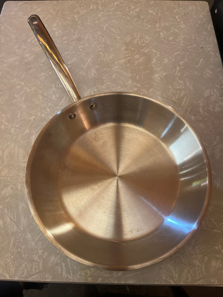 10-inch stainless steel frying pan with flared sides and riveted handle, ideal for frying and tossing. Made by Design Target, shown on a light countertop.