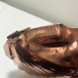 A close-up of a Large copper seashell baking pan with nickel lining with a hinged lid, embossed details, and resembling a stylized fish, used in the kitchen.