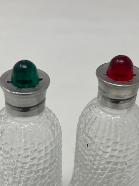 Close-up of the 1950s red and green glass salt and pepper shaker set, featuring textured glass, colorful accents, and metal hardware.