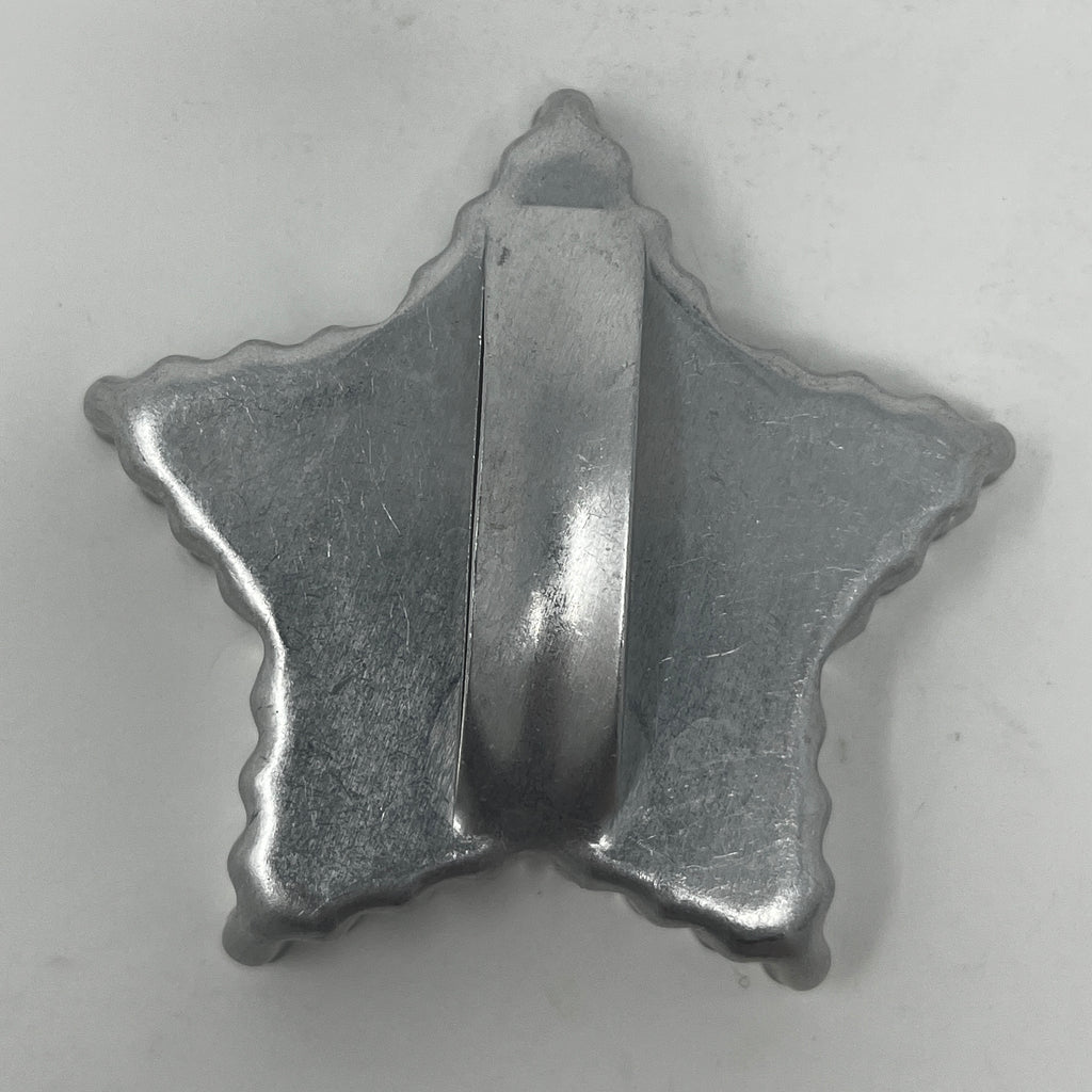 Mid century metal cookie cutters in star and moon shapes, with a close-up of the metal surface.
