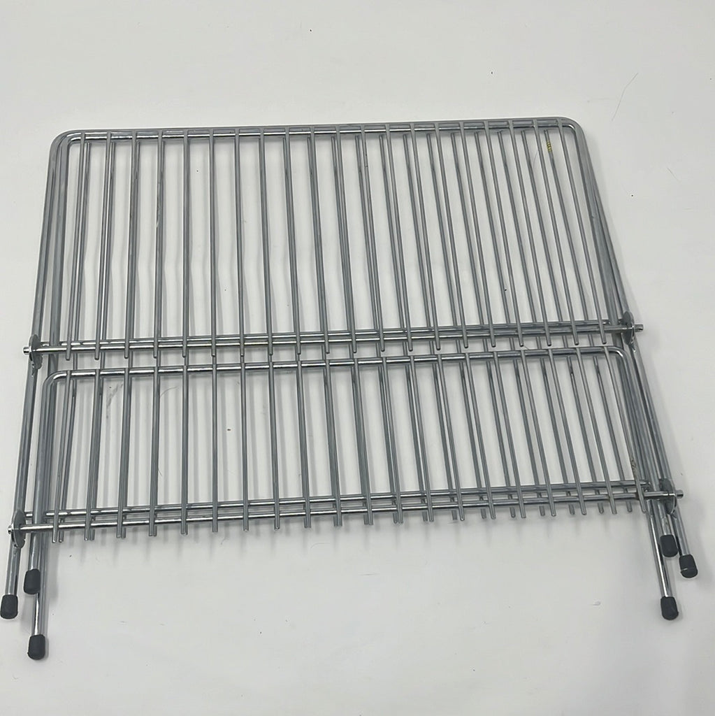 Stainless steel wire dish rack with black handles and metal grid, ideal for small kitchens or travel setups, featuring rubber pads for stability. Folded up at set on white background. From Spoons Kitchen Exchange.