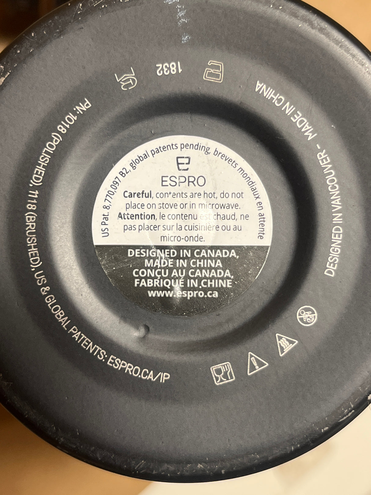 Close-up of Espro travel coffee brewer base showing logo, safety warnings, patent details, and origin markings, emphasizing its design and manufacturing information.