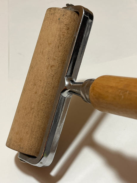 Pampered Chef double rolling pin featuring a wooden handle and cylinder in a metal frame, ideal for block printing and pressing dough or pizza seams.