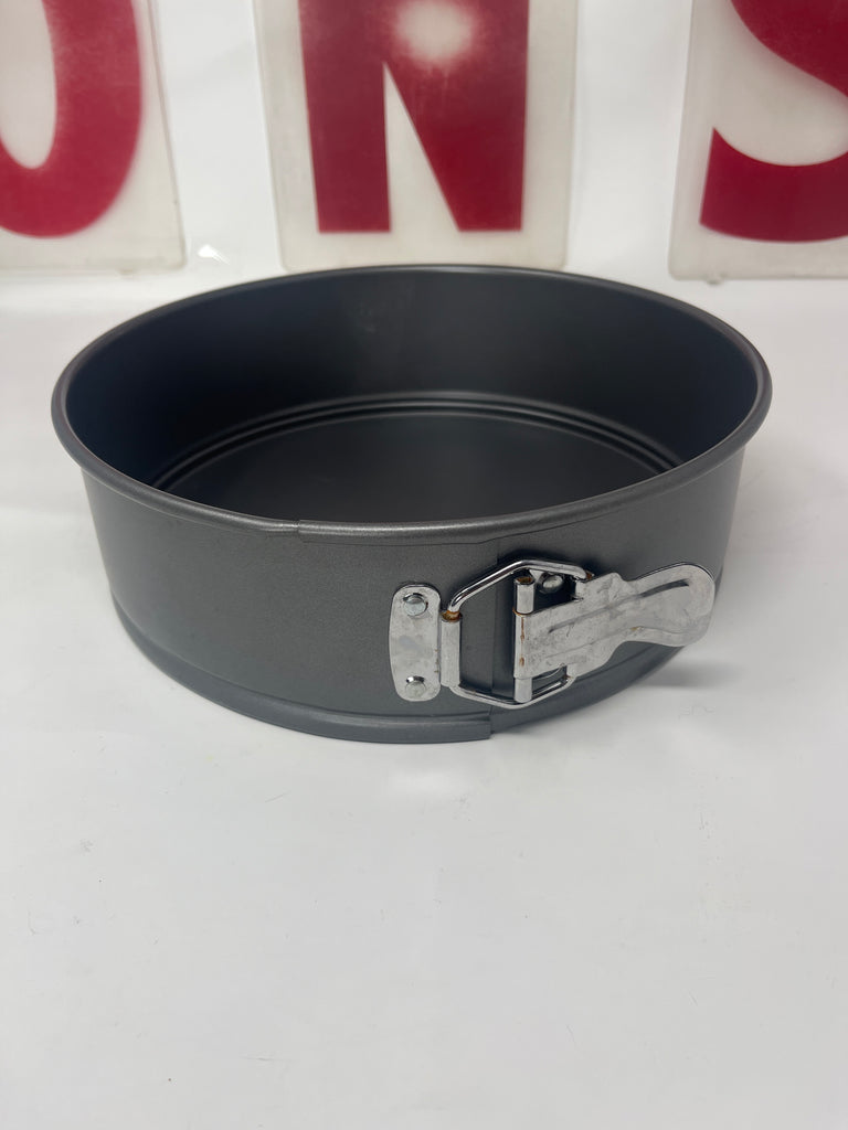 Springform baking pan, round 9-inch nonstick, with a metal buckle and handle, showing minor wear inside.