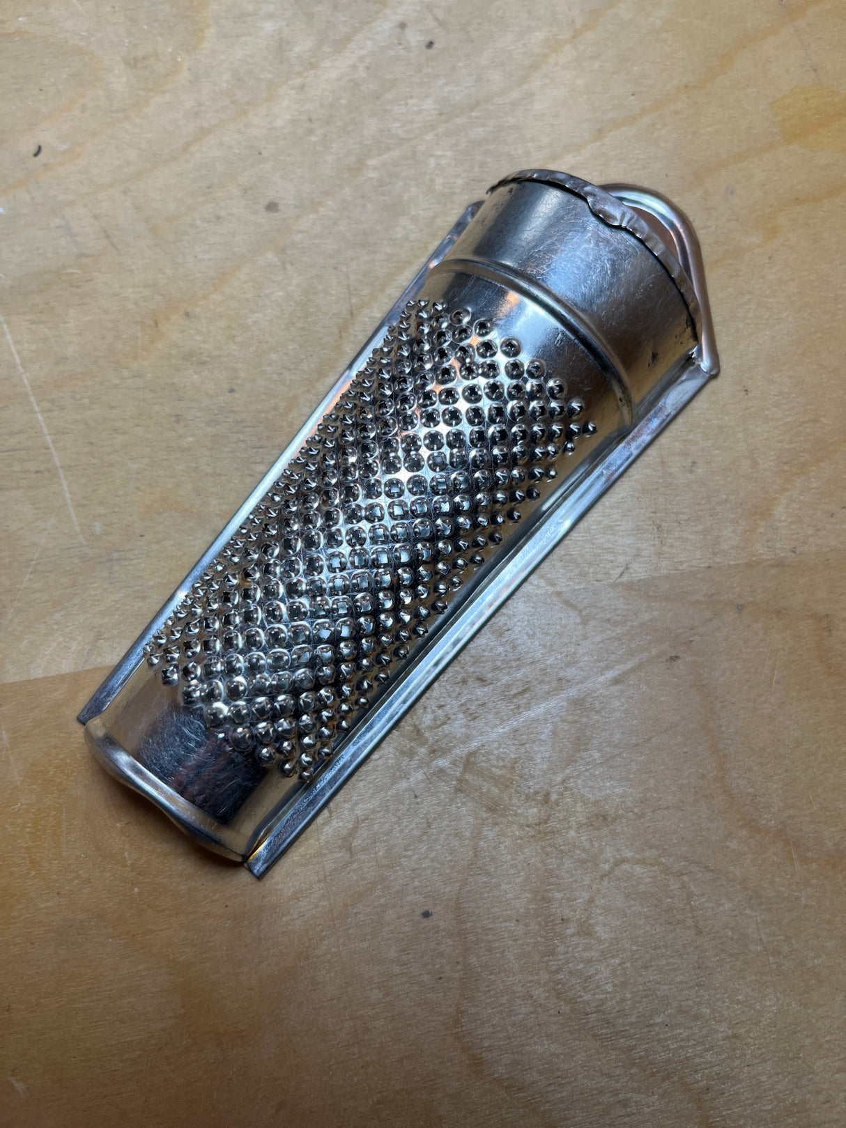 Nutmeg grater made in Germany, featuring a hand-held stainless steel design with a hinged holder for finely grating hard spices into a contained powder.