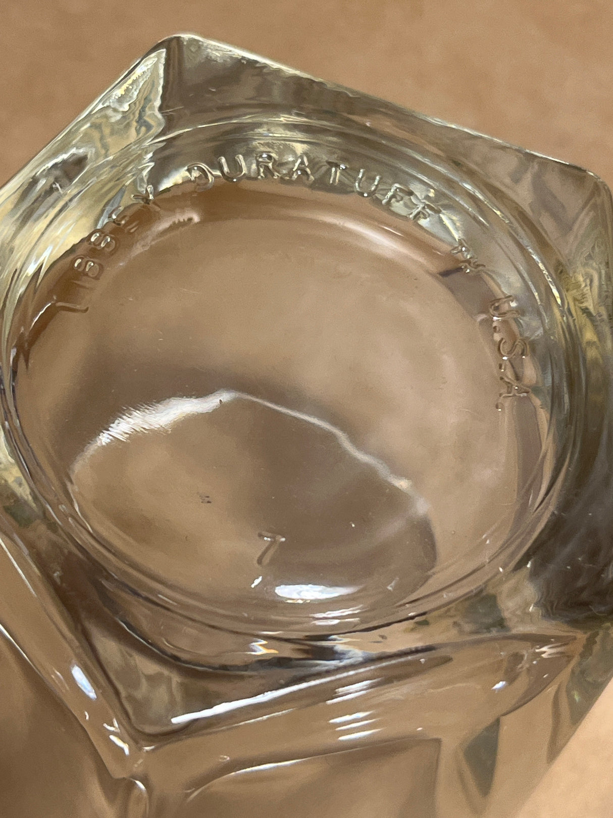 Bottom-up view of a Libbey Duratuff pentagonal whiskey tumbler glass, showing molded lettering around the rim and an embossed 7 at the center.
