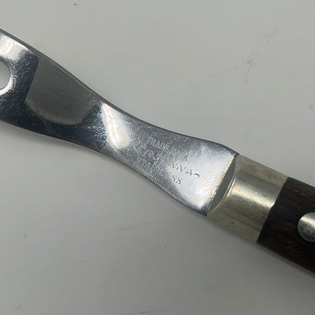 A vintage stainless steel 2-prong carving fork with a wooden handle, ideal for slicing roast meats. Close-up of a classic hand tool from the 1950s.