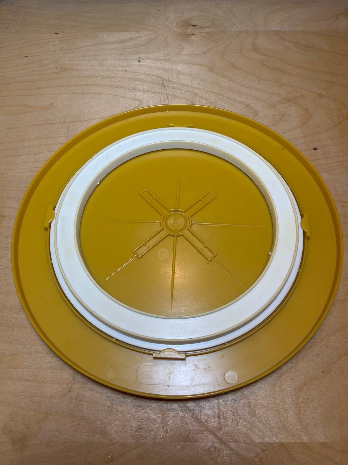 Bee Plastics harvest gold lazy Susan tray featuring a round design with an “X”-shaped rib pattern and a removable white gasket insert for secure sealing.