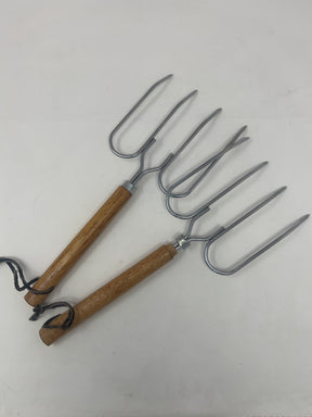 Set of two vintage roast forks with wooden handles, ideal for grilling meats and whole vegetables, showcased among other tools and kitchen utensils.