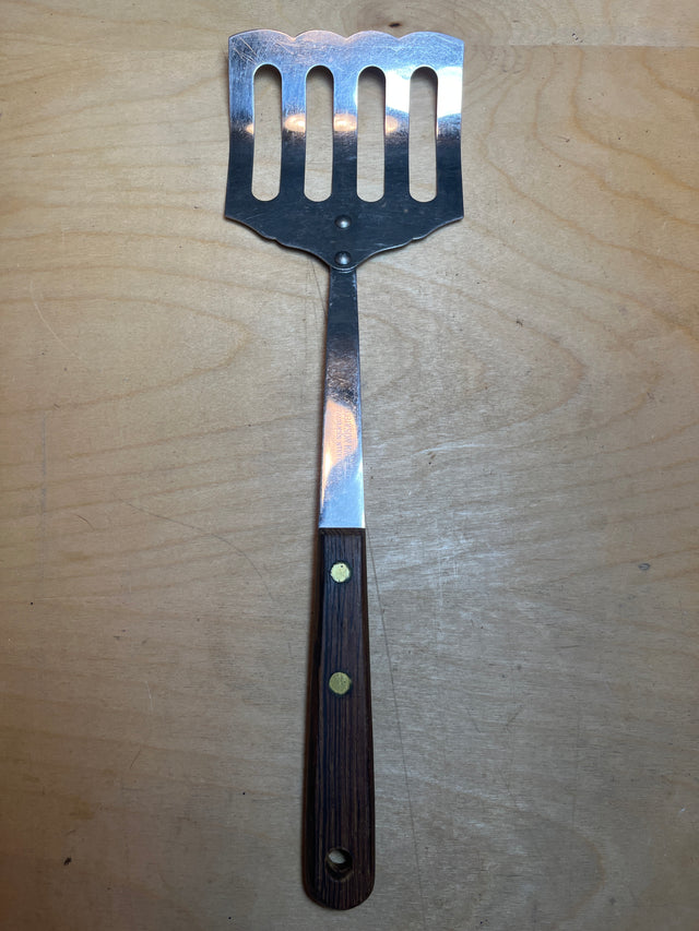 Slotted turner spatula by Robinson Knife Co., featuring a stainless steel flipper and a wooden handle, ideal for cooking pancakes, fish, or burgers.