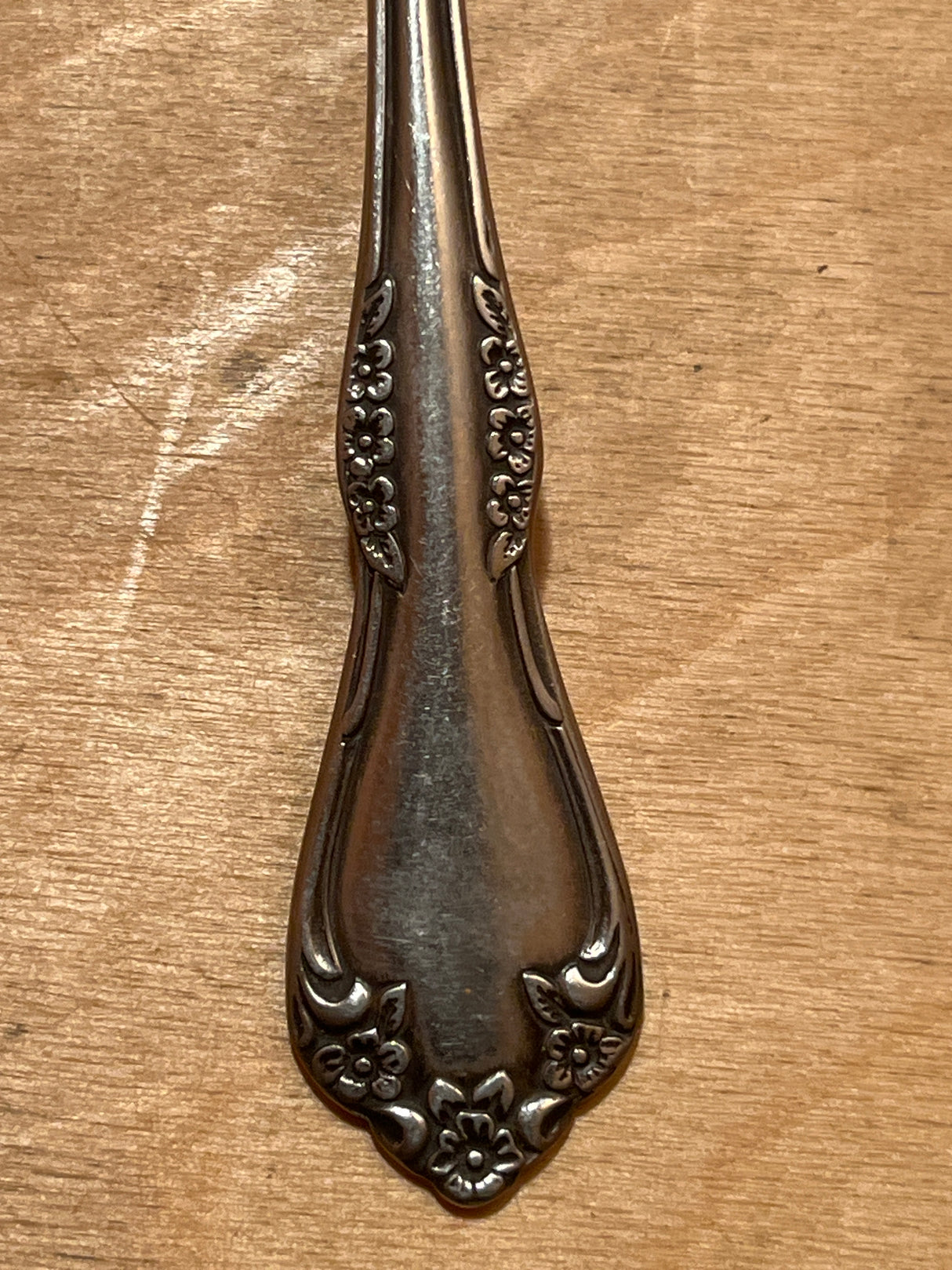 Ice tea spoon - Wm A Rogers Deluxe Oneida MANSFIELD stainless steel with a silver-plated handle featuring an embossed floral motif, displayed on a wooden surface.