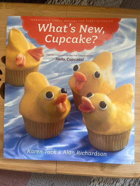 Book cover for What’s New, Cupcake? featuring a yellow cupcake shaped like a duck, highlighting creative cupcake designs from the bestselling cookbook series.