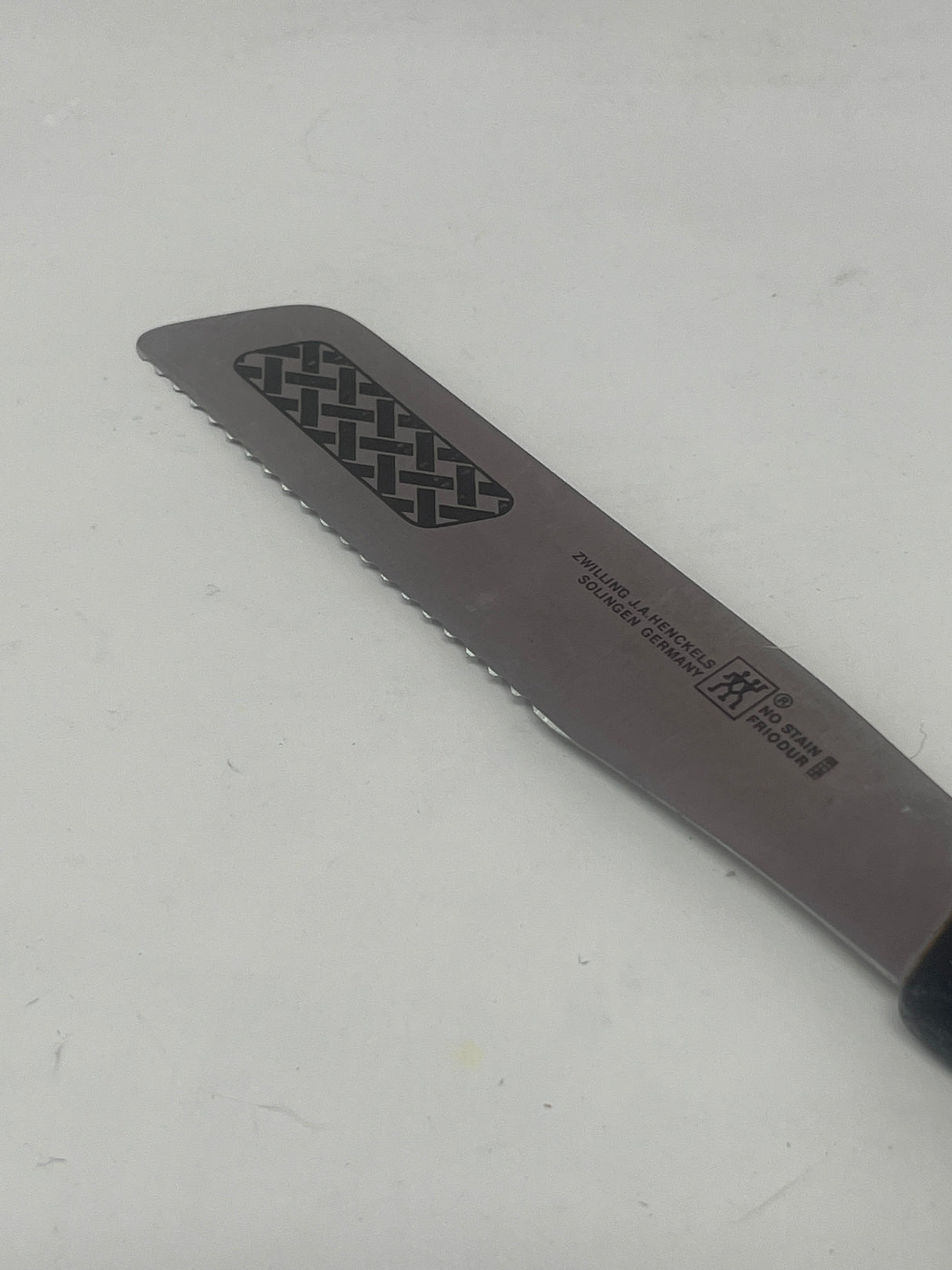 Vintage Zwilling J.A. Henckels serrated butter knife with a black handle, perfect for creating butter curls with its precise serrated edge.