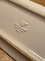 Underside of a Pfaltzgraff covered white ceramic butter dish, showing central boss and factory stamp with logo and model markings on glazed surface.