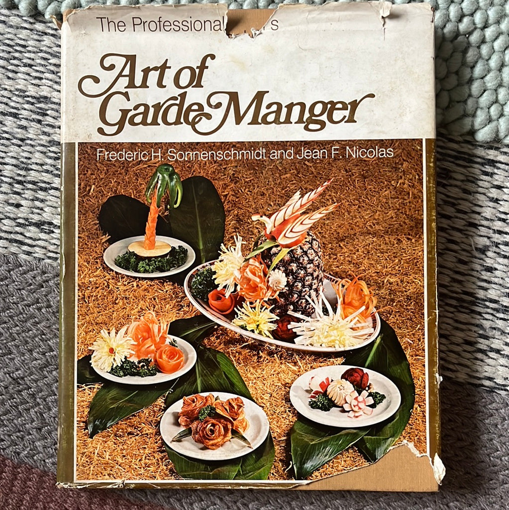 The Professional's Art of Garde Manger: Book cover with artfully arranged food on plates stacked on tropical leaves. From Spoons Kitchen Exchange.