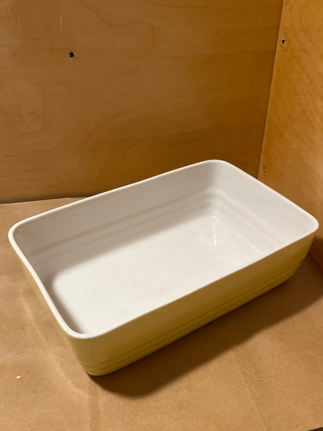 Westinghouse 1940s refrigerator dish, an empty shallow rectangular ceramic piece, sits on a wood-covered surface, showcasing its vintage-inspired design and functionality.
