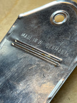 Close-up of a Nutmeg grater with “MADE IN W. GERMANY” embossed, showcasing tooling marks, stamped ridges, and a mounting hole on stainless steel.