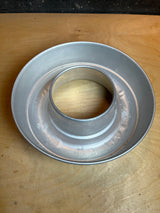 Vintage Circular Bundt pan in aluminum, featuring a round mold with a hollow center tube for even baking. Notable for its lightweight design and small dings.