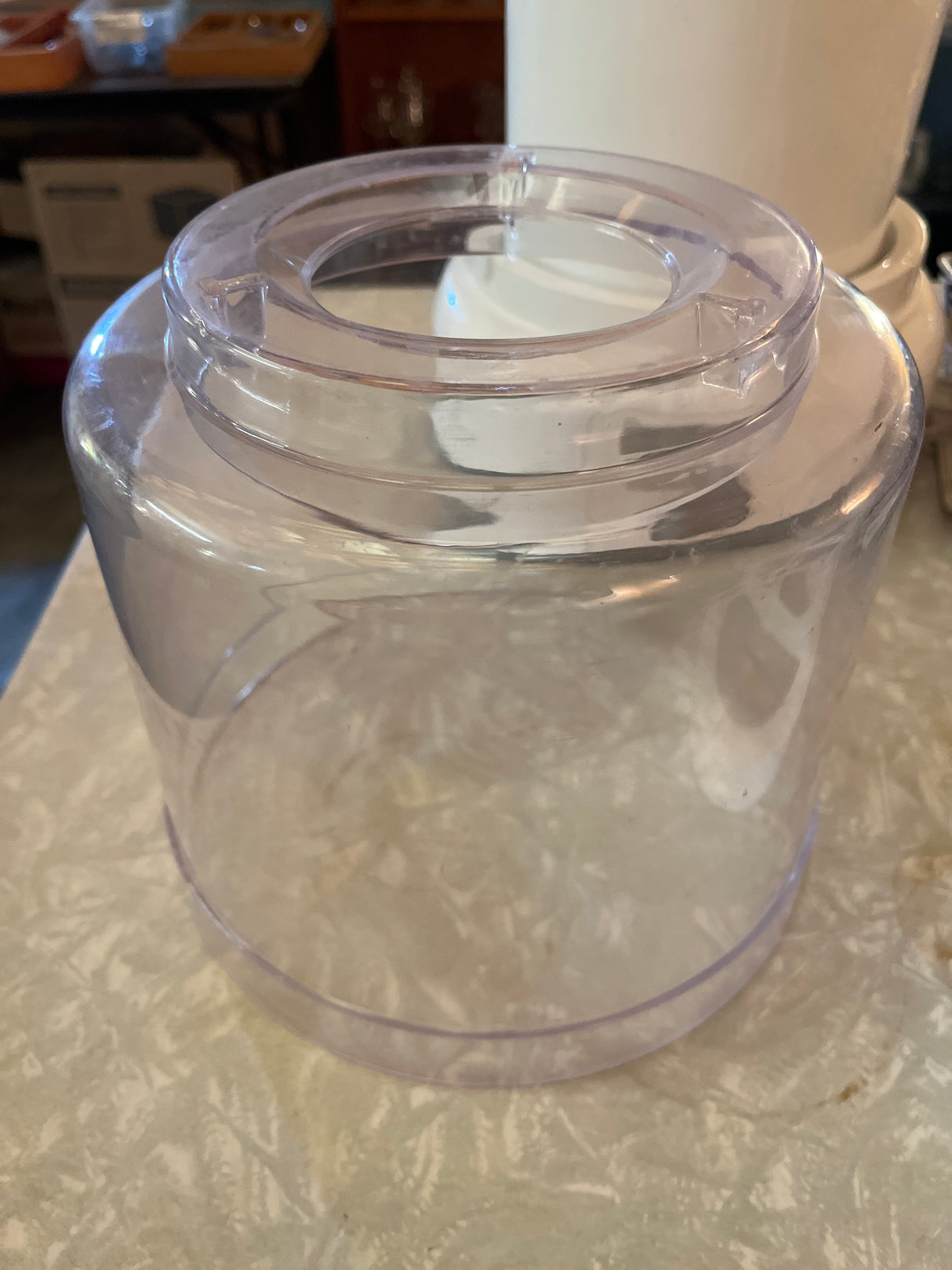 Transparent bowl component of the Automatic Ice Cream Maker - Hamilton Beach 68880, showcasing the empty cylindrical reservoir with a circular feed-tube opening on a countertop.