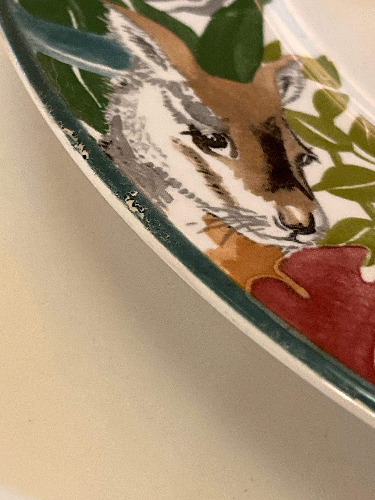 Jungle Fever dinner plate - Sango 3033 by Deborah Mallow, featuring a stylized deer or antelope head, surrounded by foliage and a red flower motif.