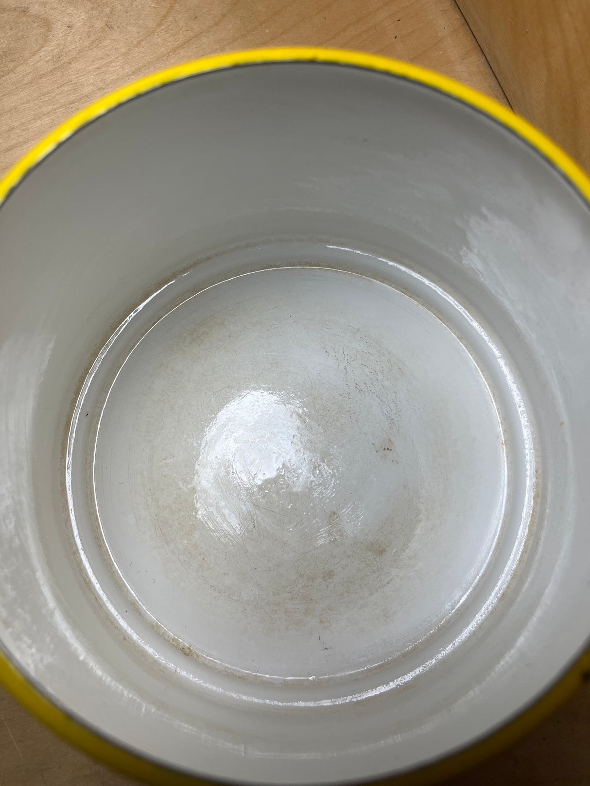 Overhead view of a vintage Michael Lax Copco fondue pot with a yellow enamel rim, showing light interior staining and a small chip on the rim.