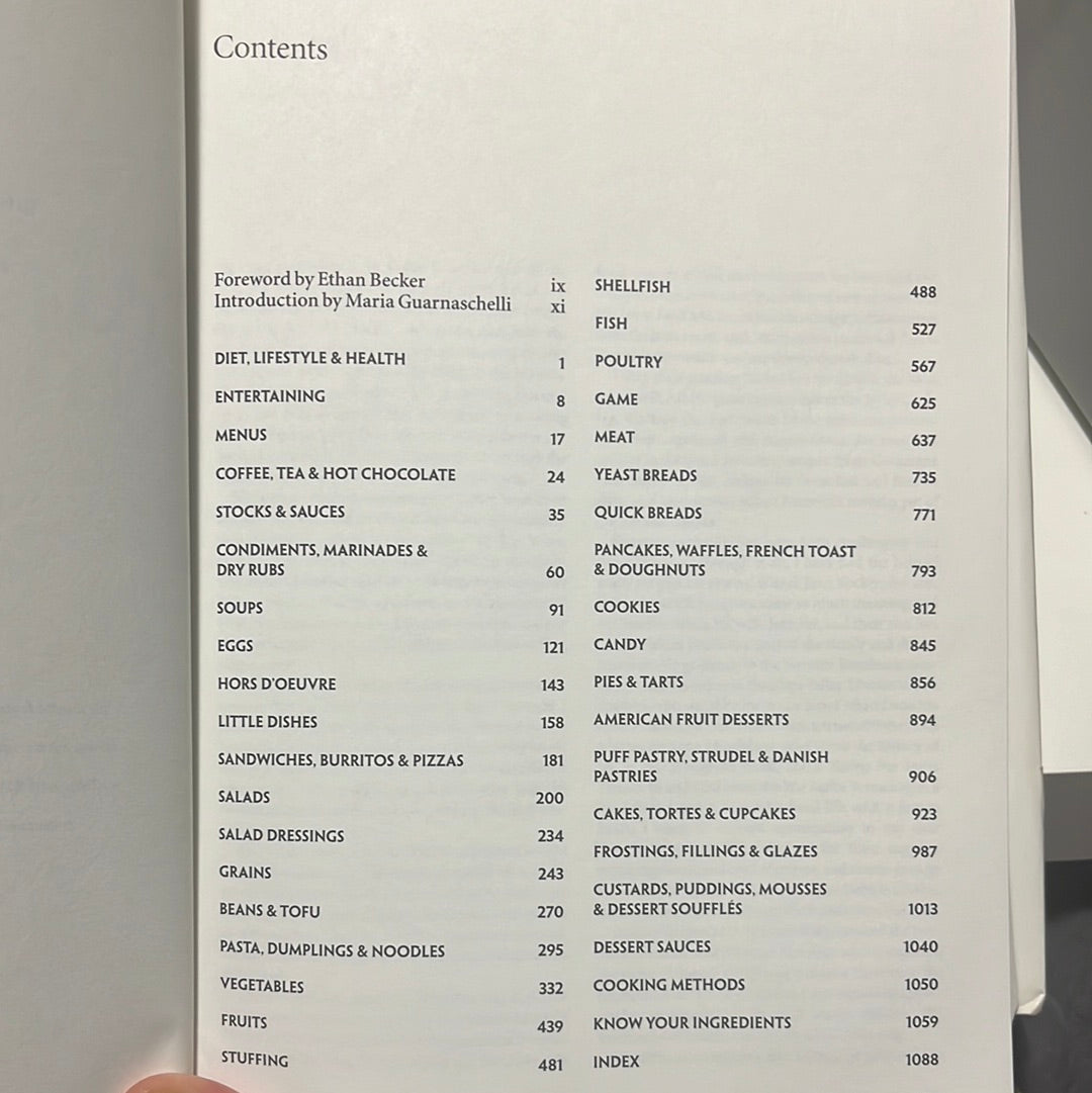 The New All Purpose Joy of Cooking book held in a hand, emphasizing its comprehensive culinary guidance and modern recipe updates.